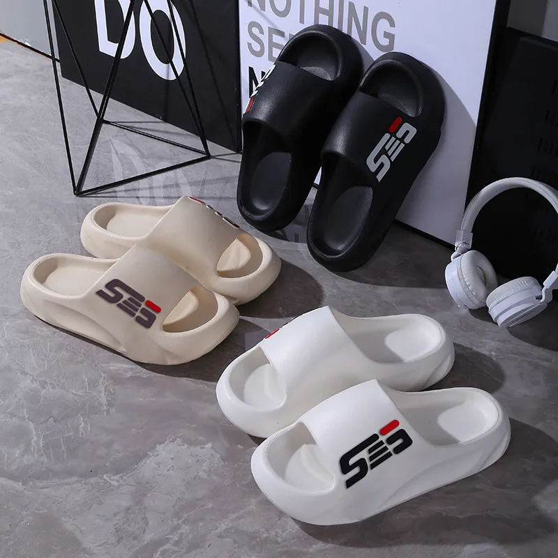 Stylish SE3 foam slide sandals in black, cream, and white colors displayed on a marble floor with modern accessories.