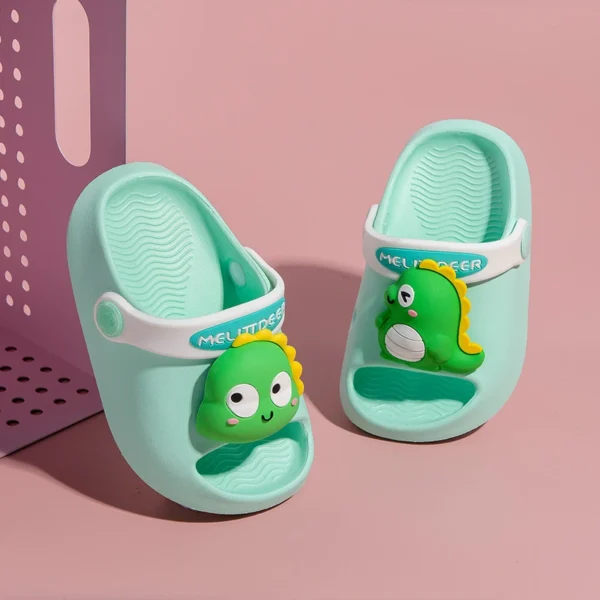 Cute apple green kids’ clogs with 3D dinosaur cartoon design and white strap on pink background.