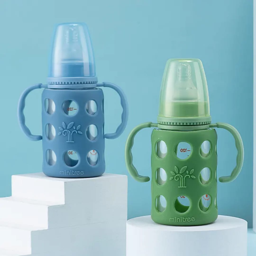 Blue BPA-free baby feeding bottle with dual handles, soft silicone anti-colic nipple, protective silicone sleeve, and easy-grip design for infants and toddlers.