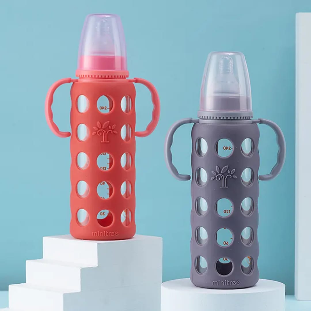 Blue BPA-free baby feeding bottle with dual handles, soft silicone anti-colic nipple, protective silicone sleeve, and easy-grip design for infants and toddlers.